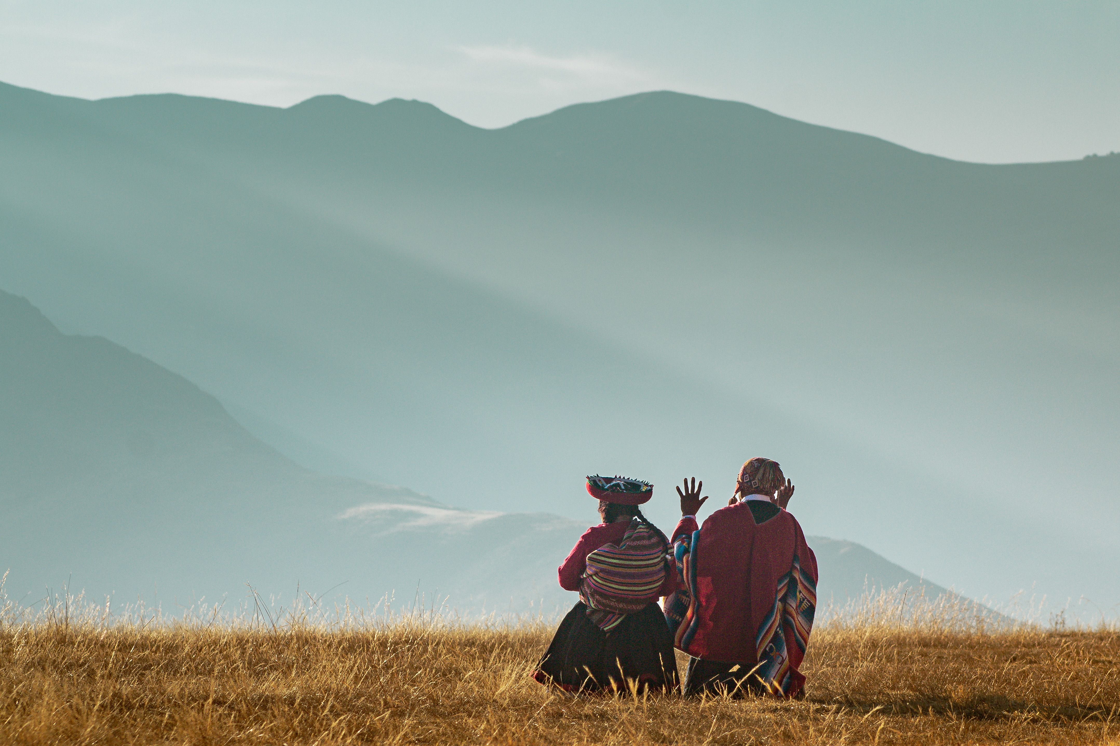 Two Andean people in front of a mountain.